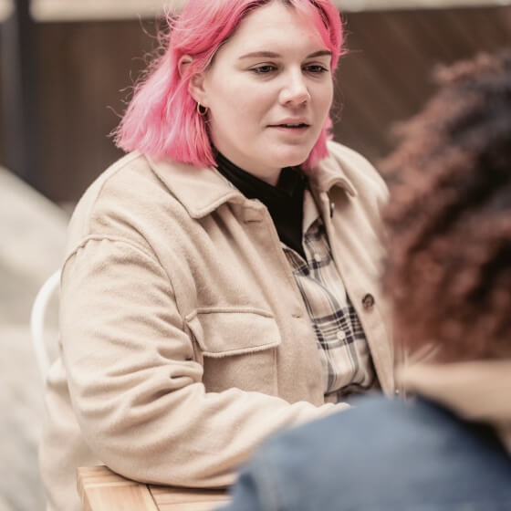 a woman with pink hair sitting at a table