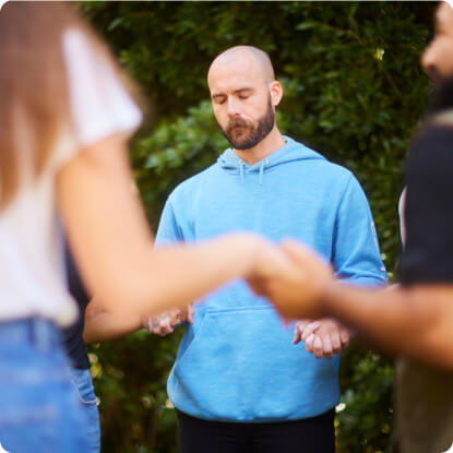 a man in a blue hoodie holding hands with other people in the background